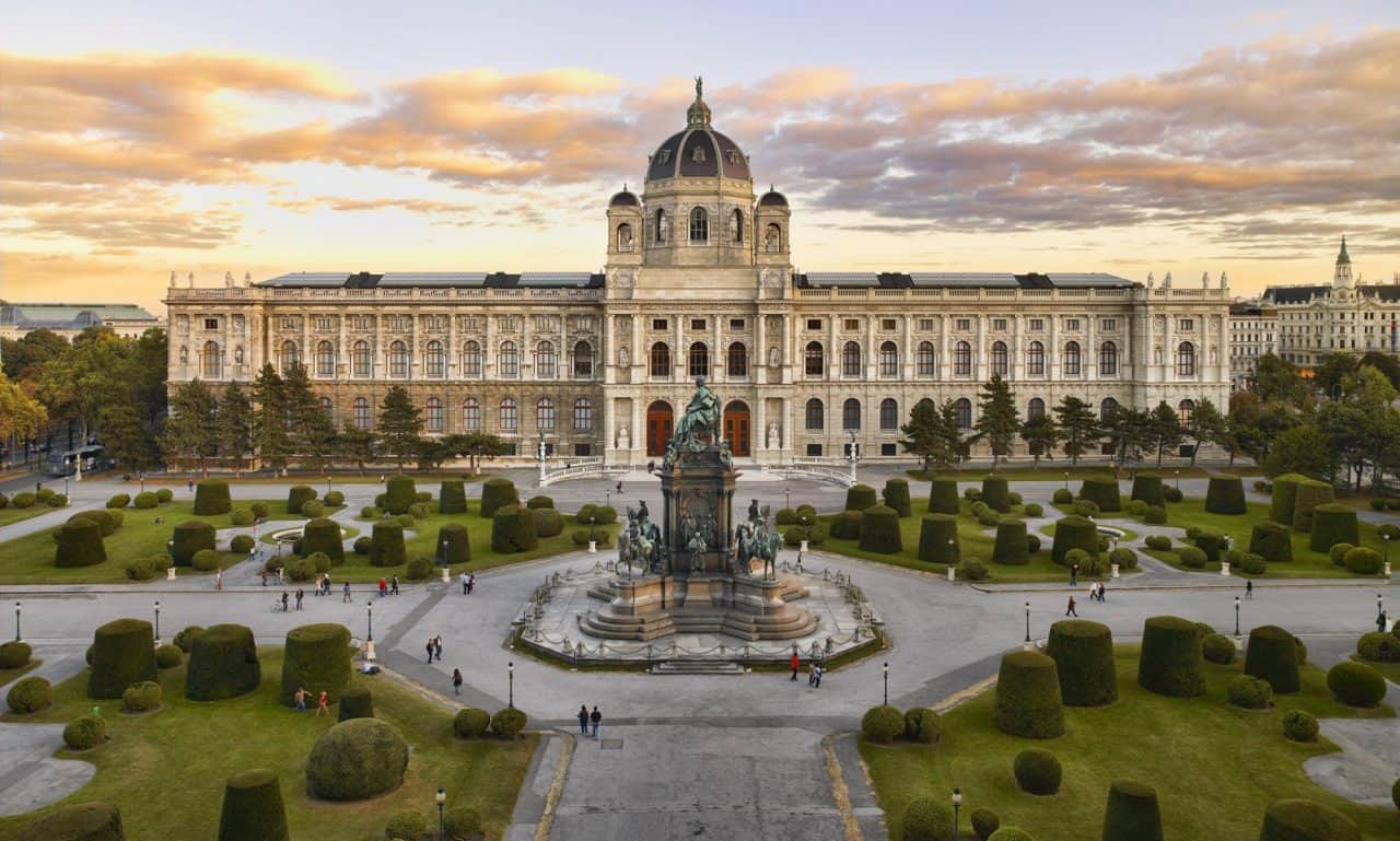 Ein Bild vom Kunsthistorischen Museum in Wien, davor ist der Vorplatz zwischen den Museen zu erkennen, dahinter der Sonnenuntergang