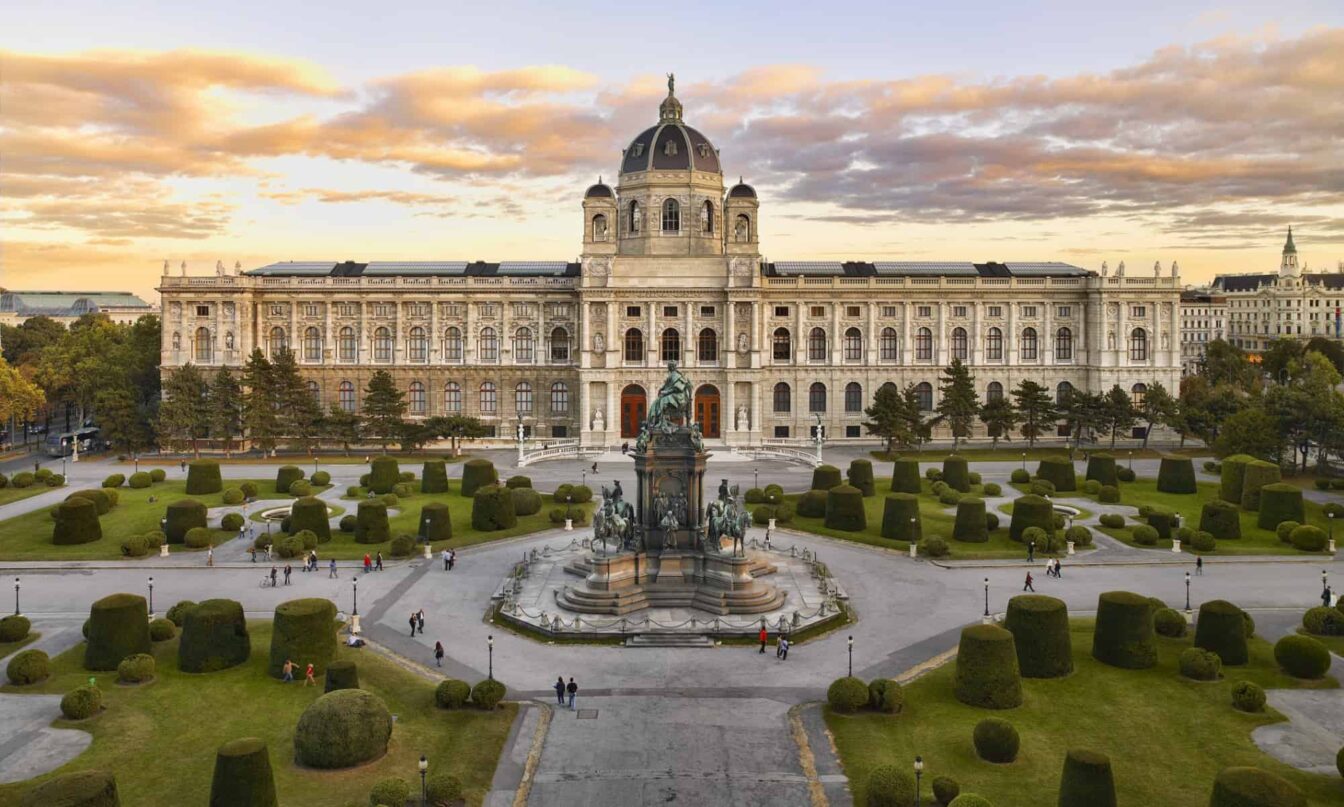 Günstige Kultur in Wien: Ein Bild vom Kunsthistorischen Museum in Wien, davor ist der Vorplatz zwischen den Museen zu erkennen, dahinter der Sonnenuntergang