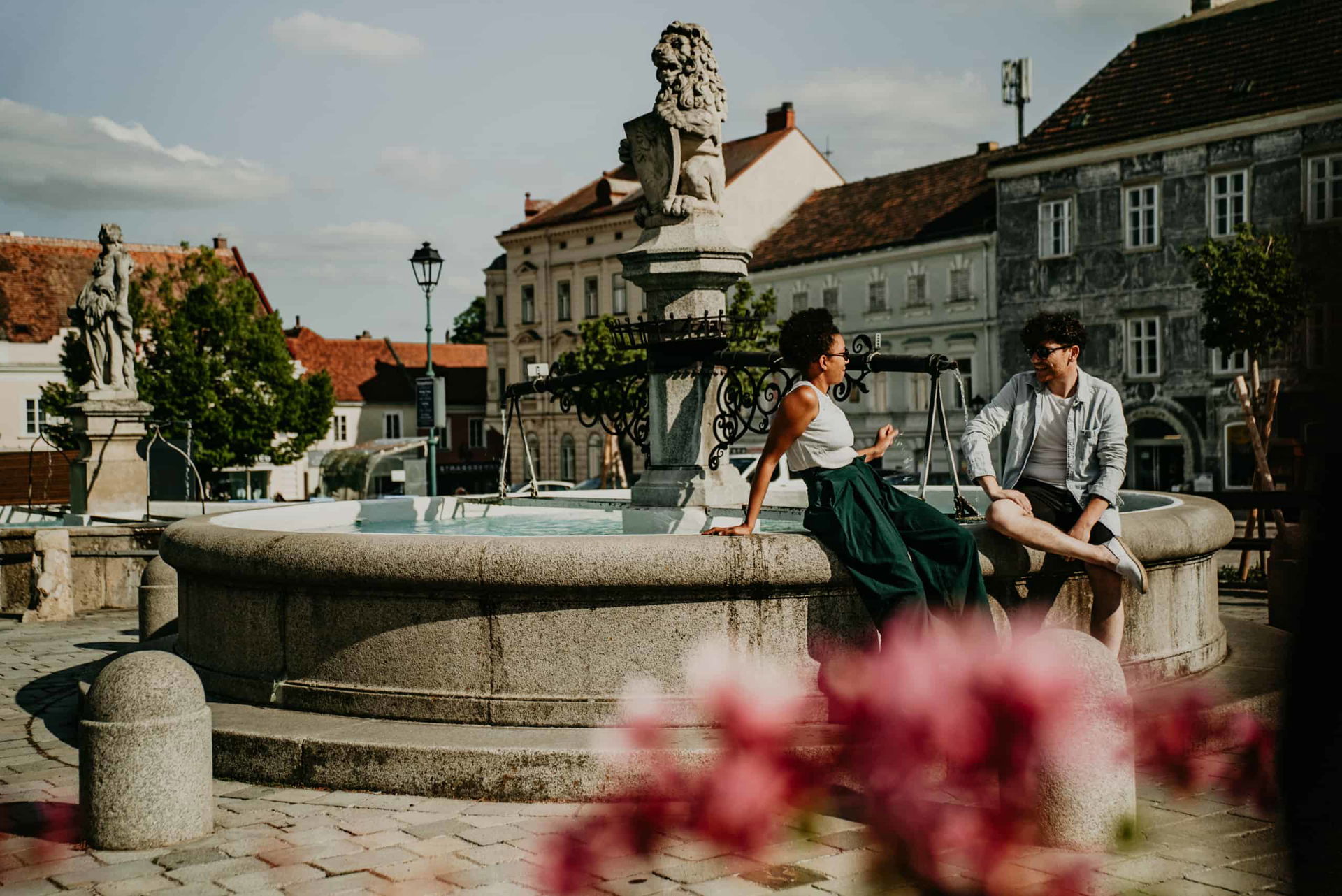 Zwei Personen sitzen auf einem Brunnen im Zentrum von Retz in Niederösterreich und sind im Gespräch.