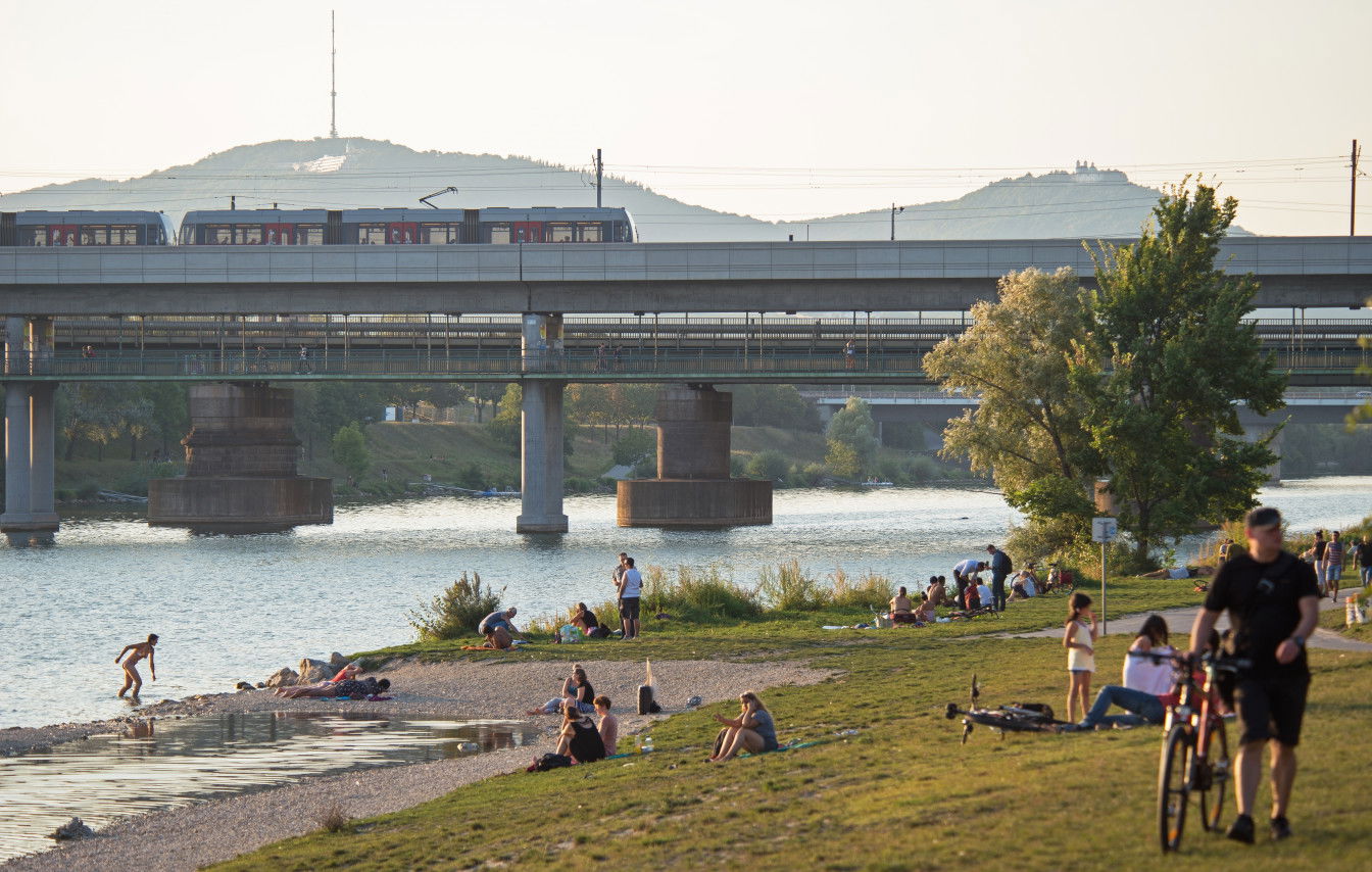 Menschen auf der Donauinsel: Im Hintergrund die U6 bei der Station Neue Donau