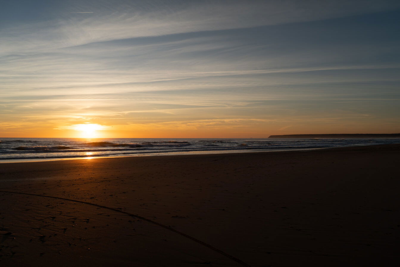 Sonnenuntergang am Meer mit sanften Wellen und leerem Sandstrand – stimmungsvolle Abendstimmung an der Küste, perfekt für romantische Strandspaziergänge und Naturfotografie.