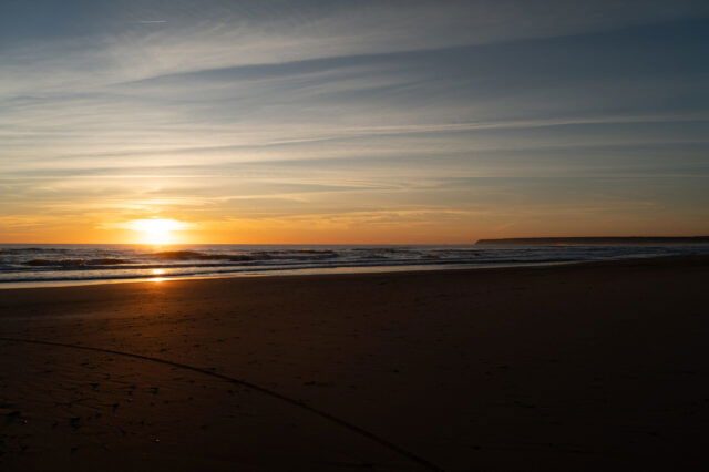 Sonnenuntergang am Meer mit sanften Wellen und leerem Sandstrand – stimmungsvolle Abendstimmung an der Küste, perfekt für romantische Strandspaziergänge und Naturfotografie.