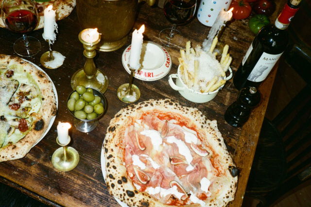 Pizza mit Kerzen und Wein am Tisch