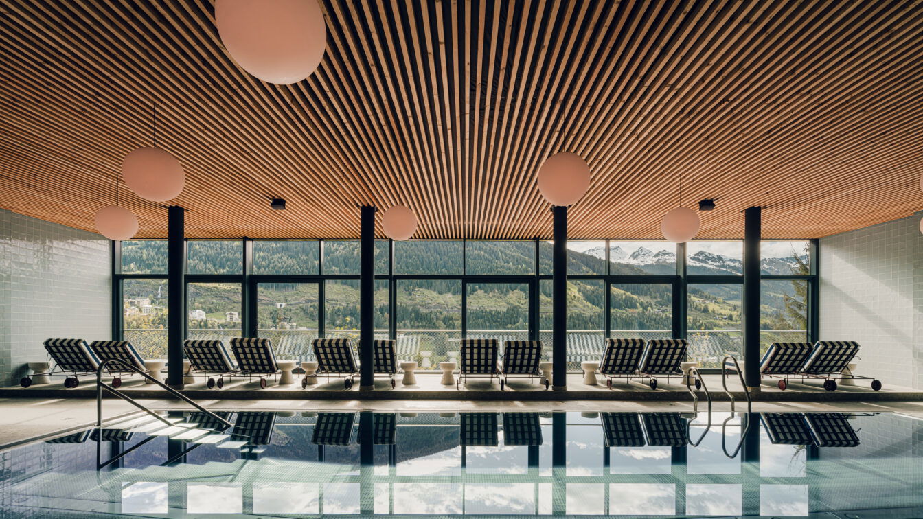 (c) PION Studio Modernes Designhotel the comodo mit stilvollem Wellnessbereich und elegantem Zimmer – lichtdurchflutetes Hallenbad mit Liegen und Designerleuchten sowie gemütliches Schlafzimmer mit hochwertiger Einrichtung und skandinavischem Flair.