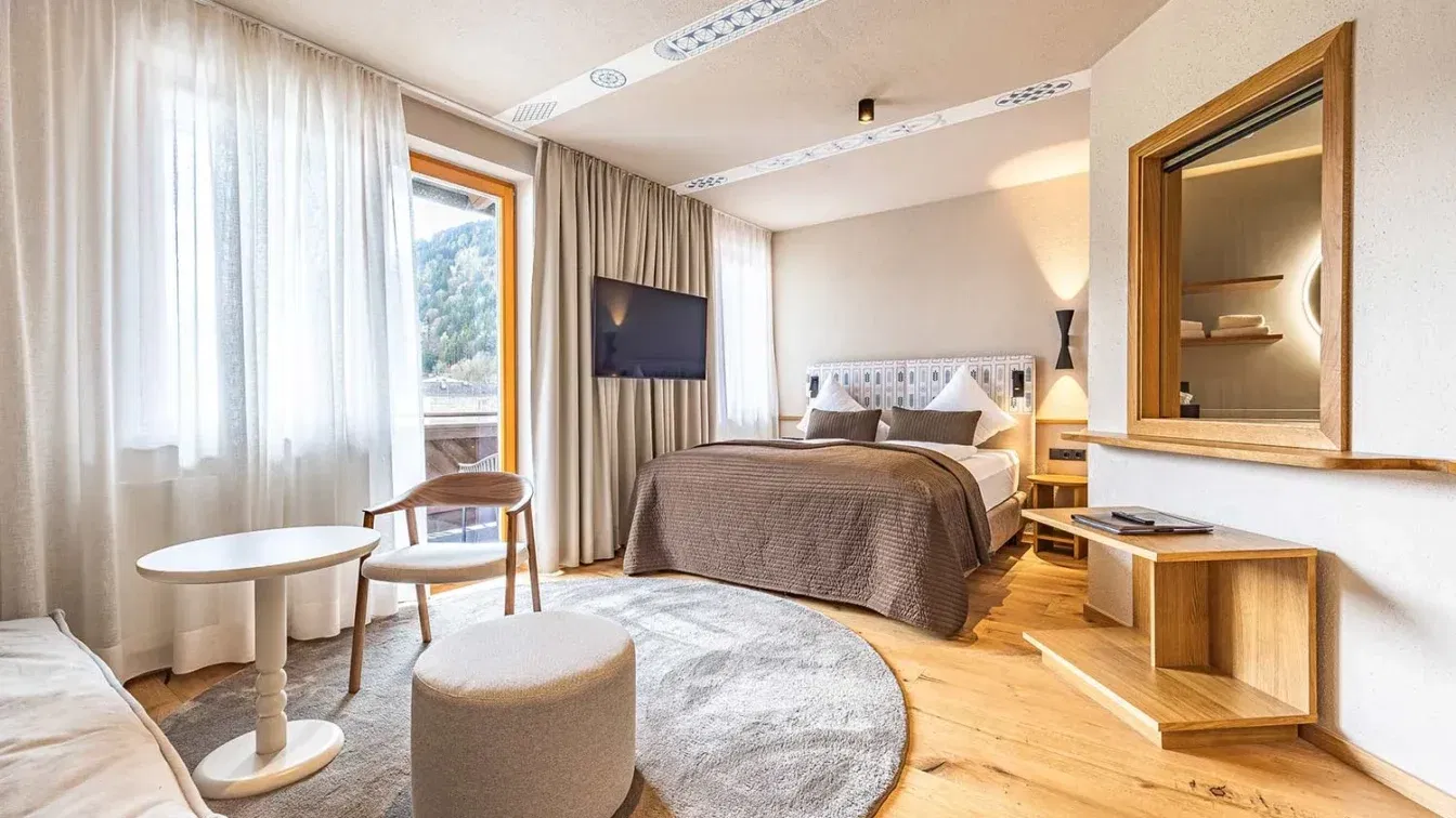 (c) Johannes Radlwimmer Ein helles Hotelzimmer mit Sofa, Bett und cremefarbenen Möbel.