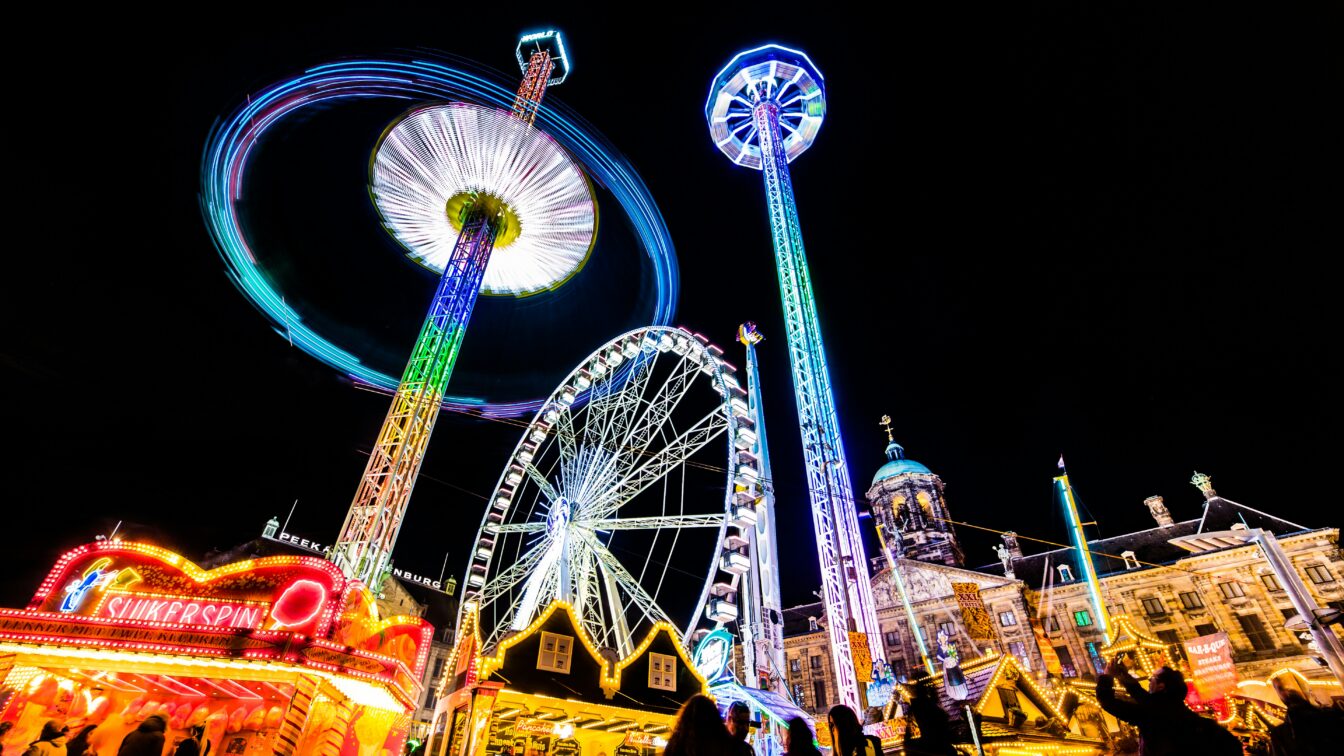 (c) redcharlie | Unsplash Jahrmarkt am Abend mit bunten Lichtern