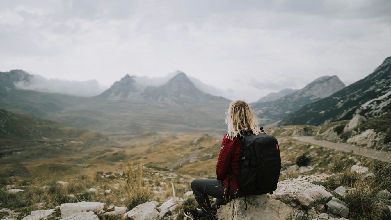 (c) Patrik Laszlo | Unsplash Frau mit Rucksack, Backpack, Blick auf Berge