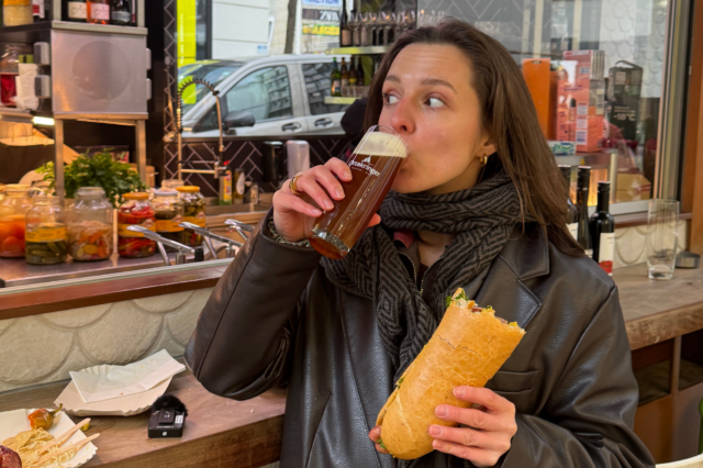Frau mit Bier und Hot Dog beim Wiener Würstelstand