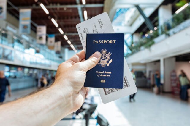 eine Hand, die Reisepass und Boarding Pass am Flughafen hält