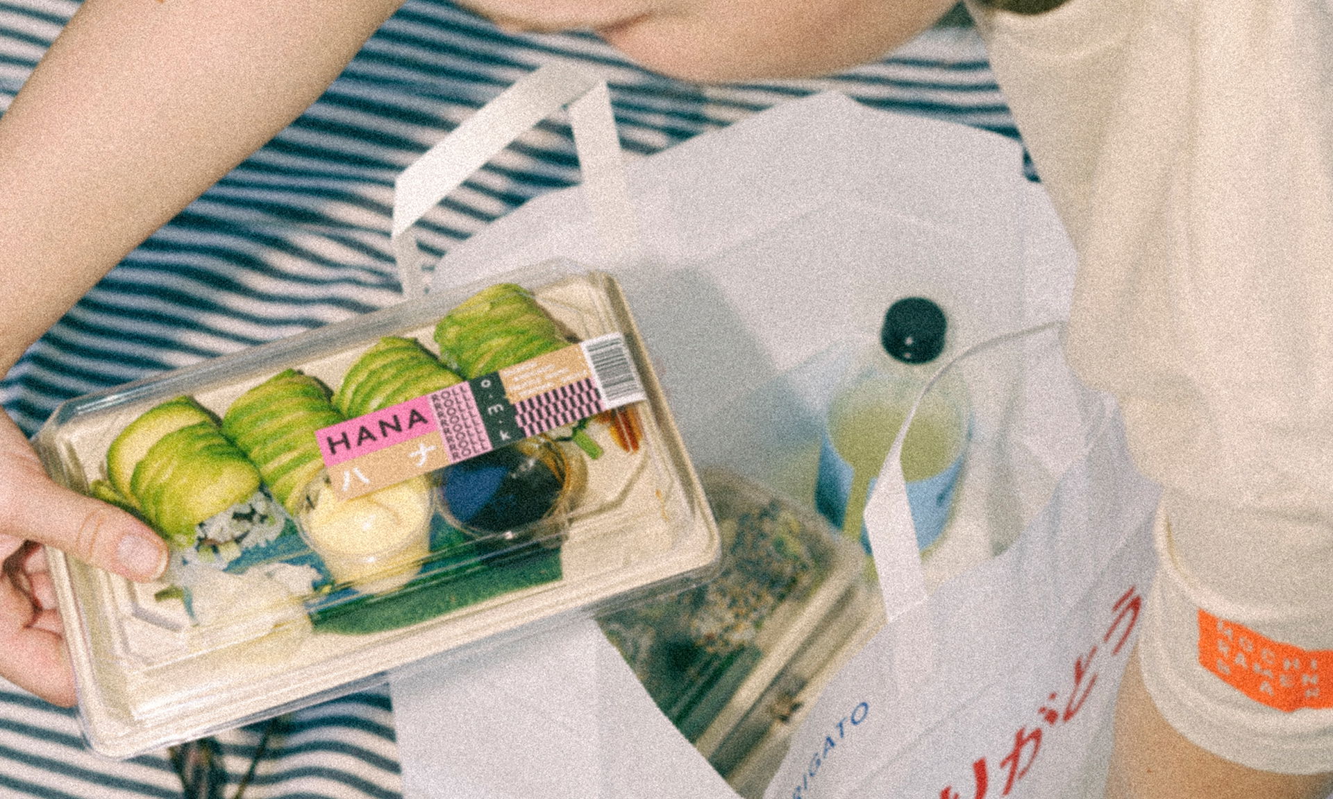Sushi auf einer Takeaway Tüte auf einer gestreiften Picknickdecke