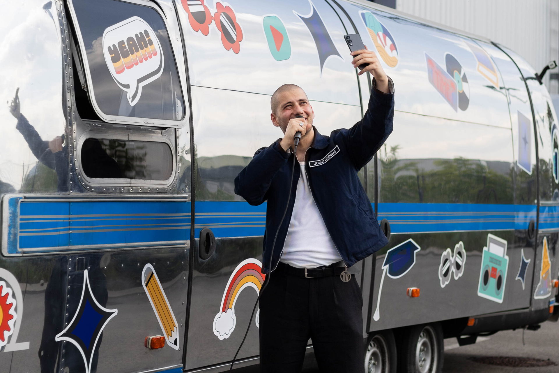 Jugo Ürdens vor dem Samsung Roadshow Truck mit einem Handy und Mikrofon in der Hand