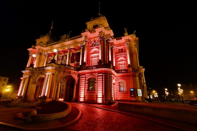 Ein großes, imposantes Gebäude, das rot beleuchtet wird bei Nacht.