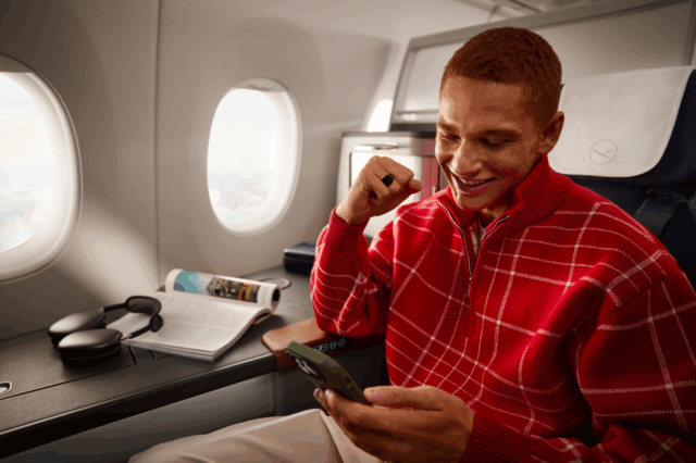 (c) Lufthansa Allegris Ein junger Mann in rotem Pullover, der in der First Class eines Lufthansa Flugzeugs sitzt.