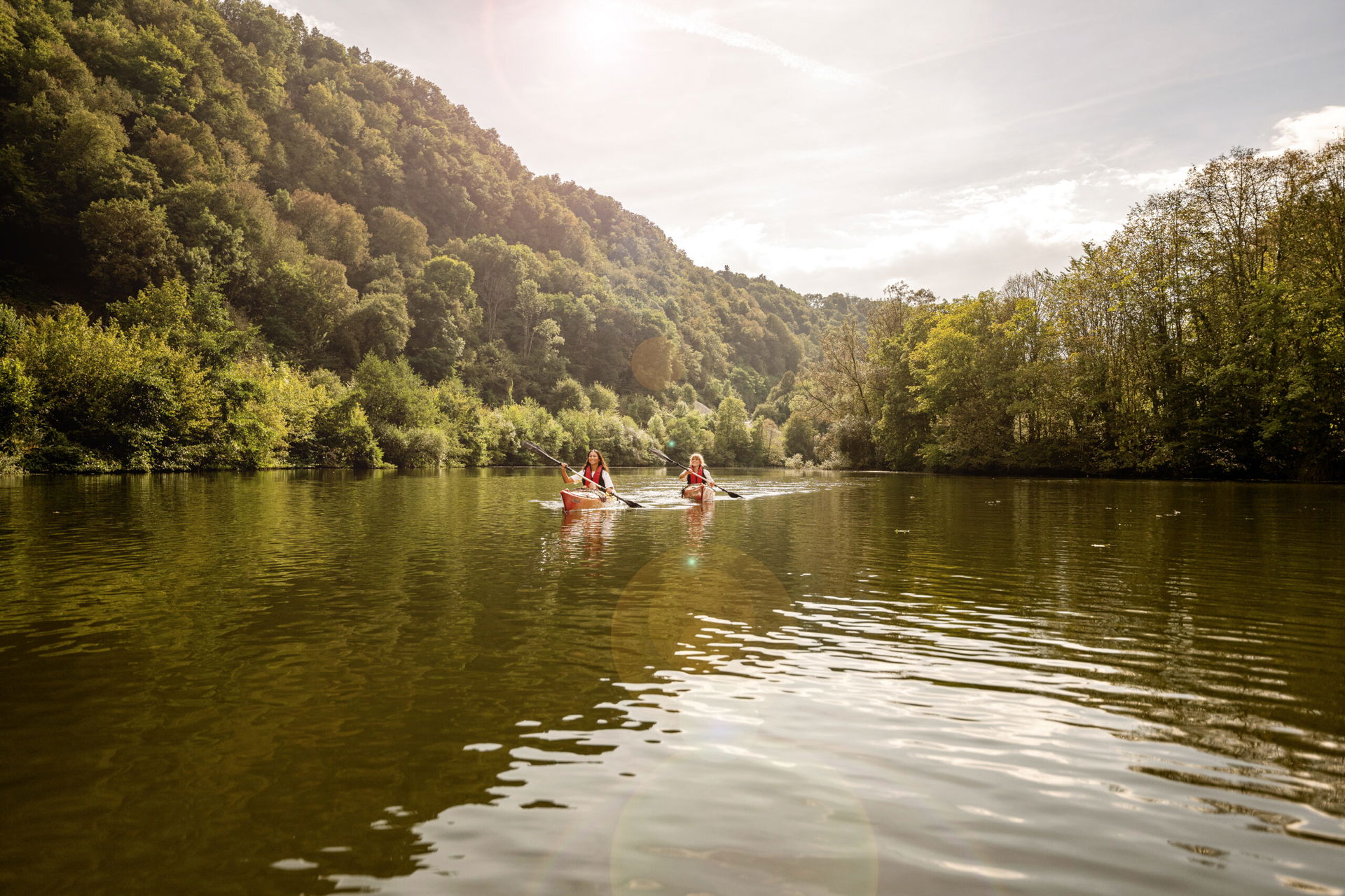 Zwei Personen mit Kanu die durch das Flusstal der Lahn paddeln