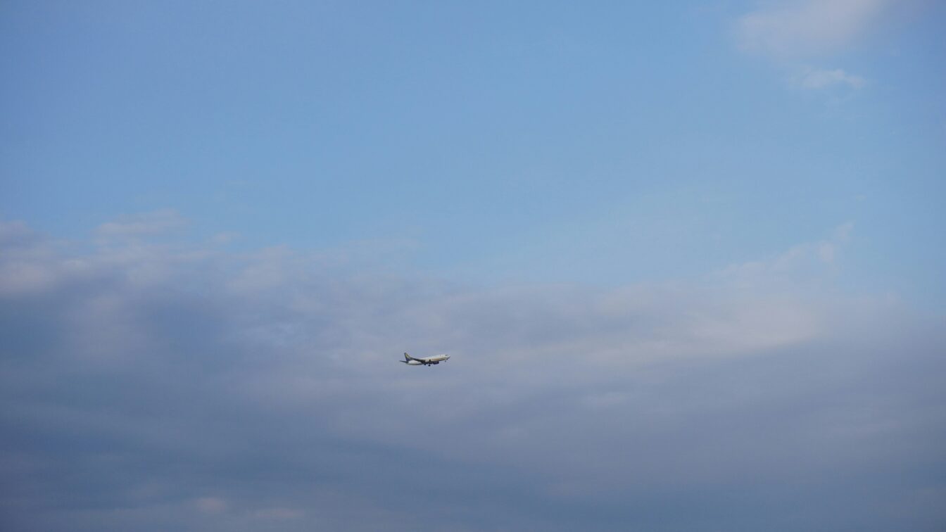 (c) Reed Lee | unsplash Flugzeug einer Billigfluglinie beim Landeanflug vor bewölktem Himmel – Symbolbild für günstiges Fliegen und versteckte Zusatzkosten bei Low-Cost-Airlines.
