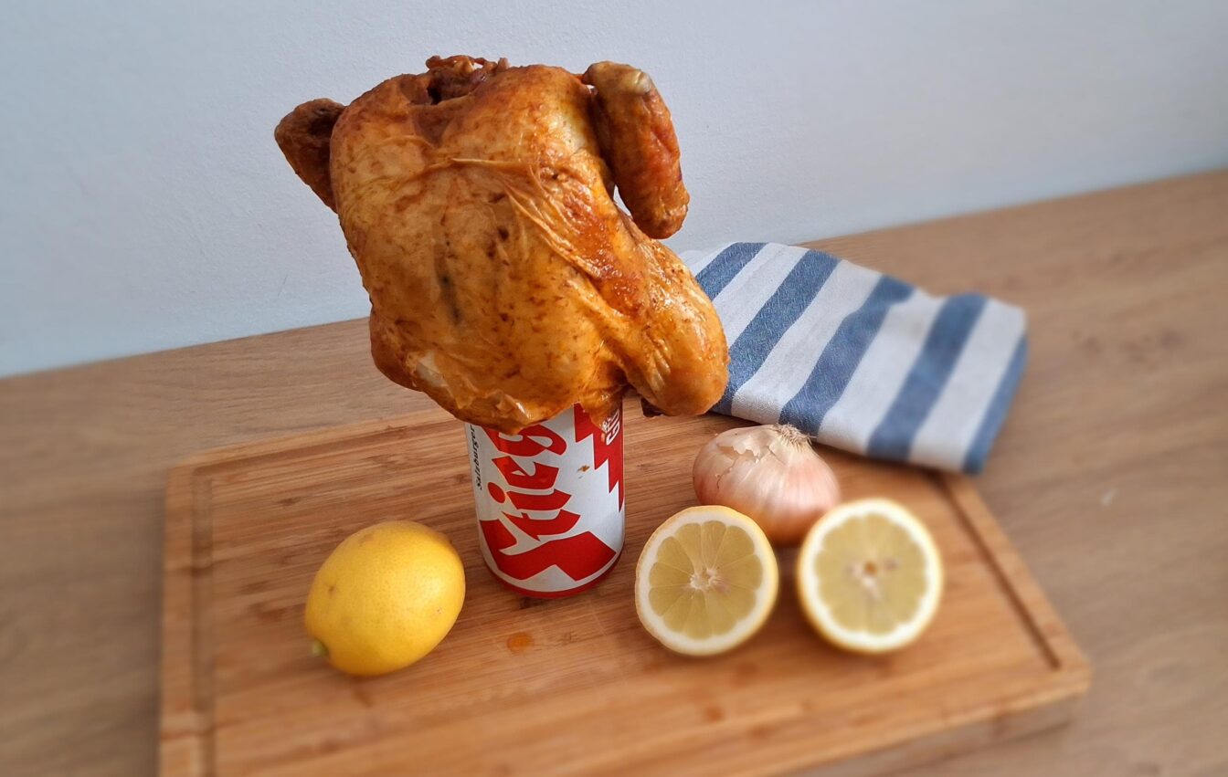 Grillhuhn auf einer Stiegl Bierdose mit Zitronen im Vordergrund