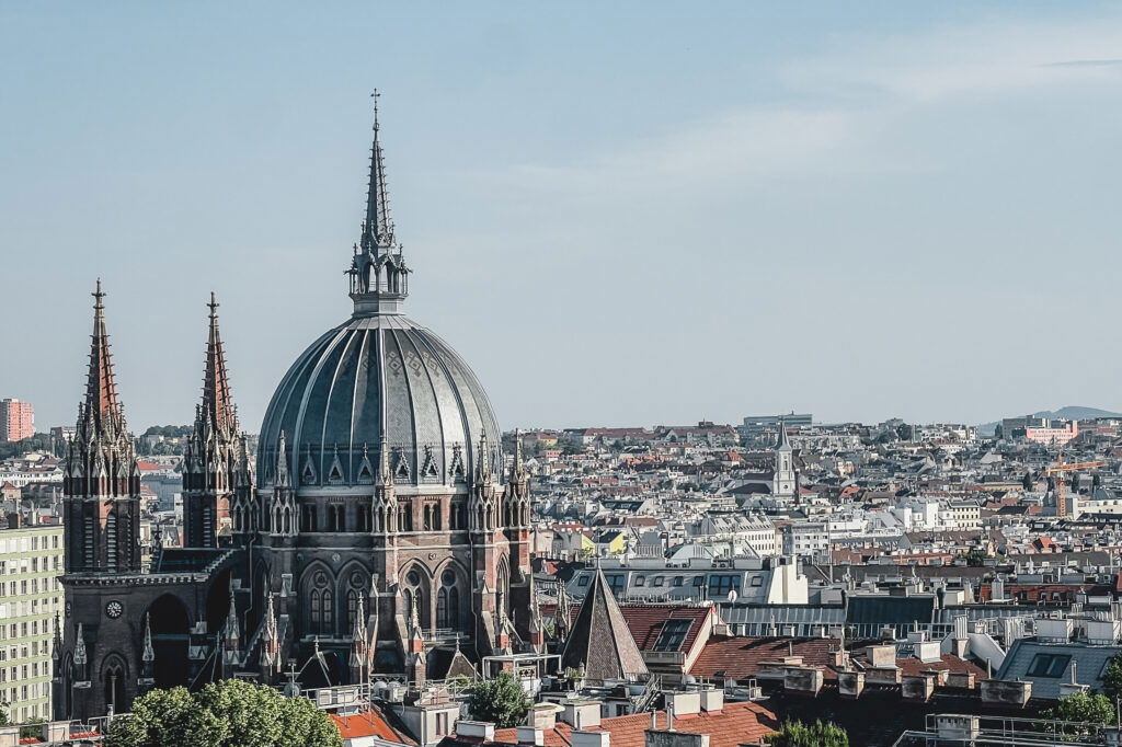 Blick über Wien an einem Sommerabend, der die Skyline freigibt und die Kirche Maria vom Siege zeigt.