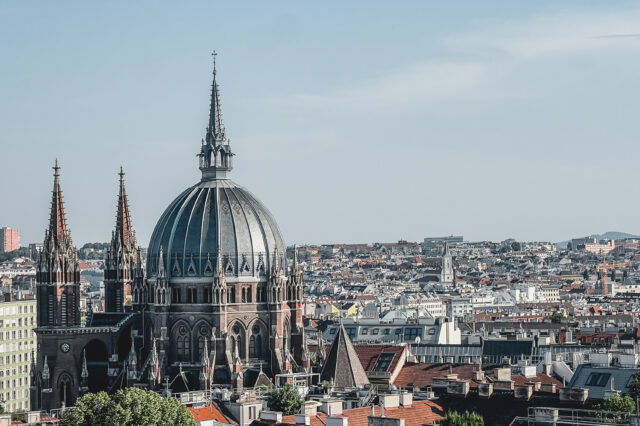 Blick über Wien an einem Sommerabend, der die Skyline freigibt und die Kirche Maria vom Siege zeigt.