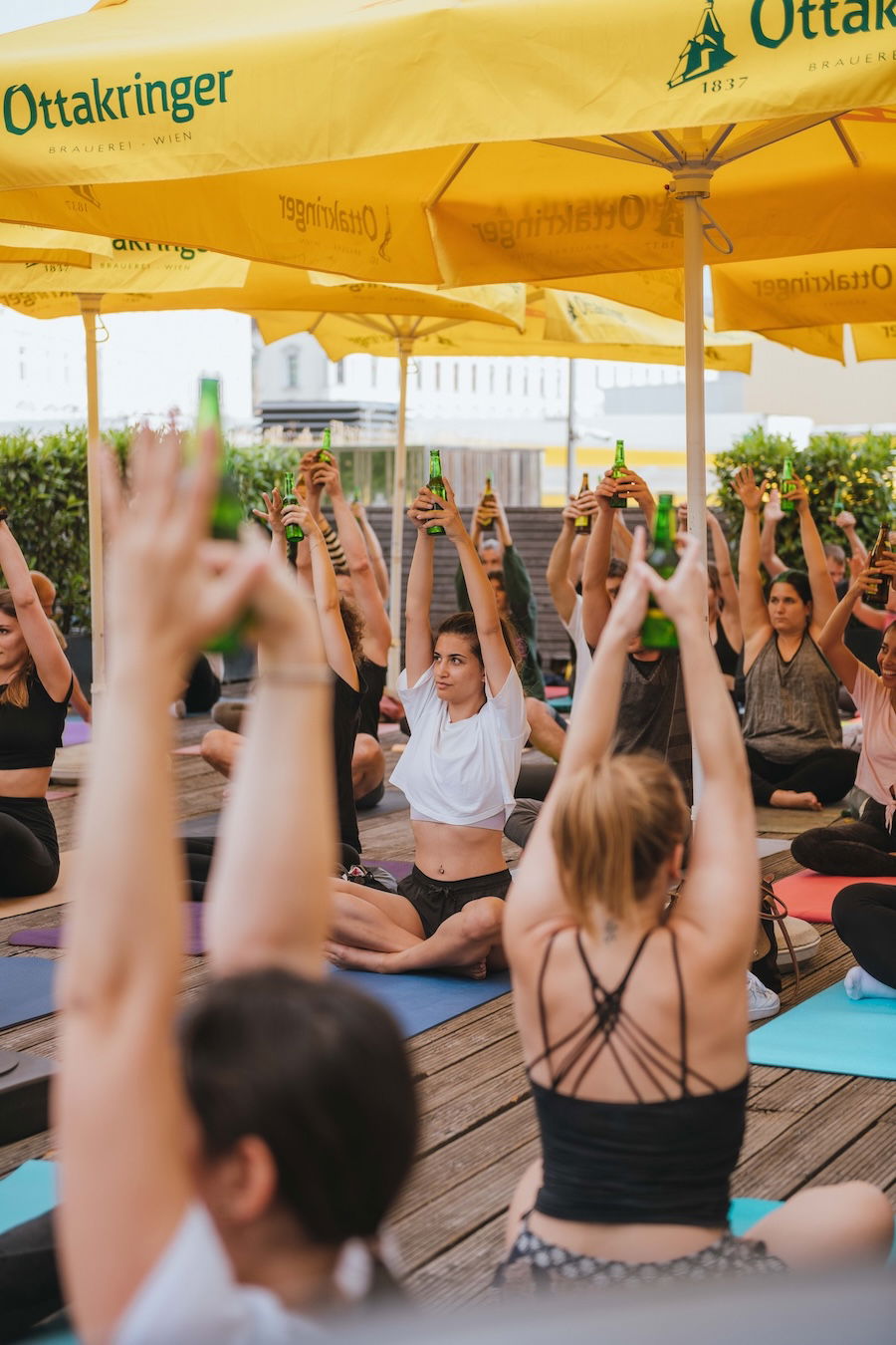 Menschen machen Yoga mit Bierflasche in der Hand beim Ottakringer Bierfest