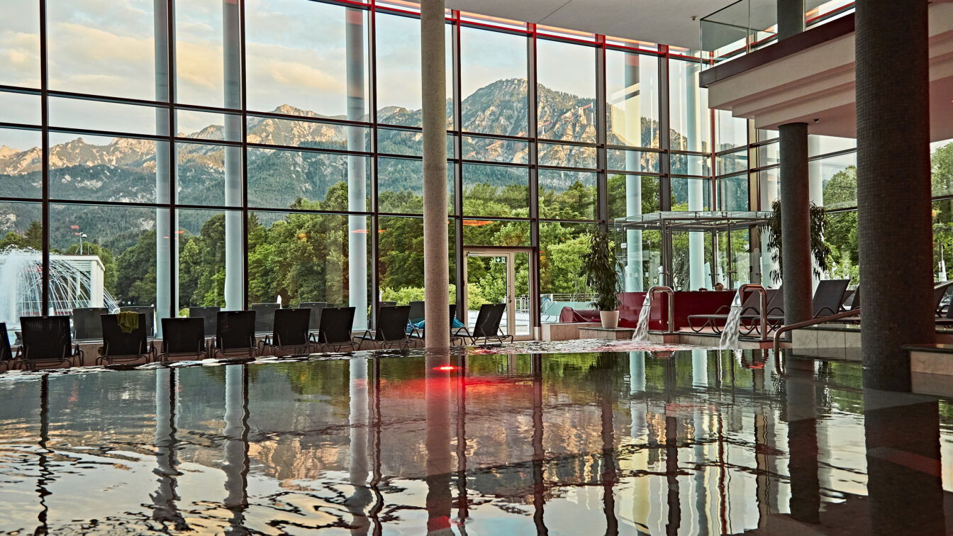 Die RupertusTherme in Bad Reichenhall. (c) Bayern by Gert Krautbauer Eine Glasfassade, die sich im Wasser eines Pools spiegelt.