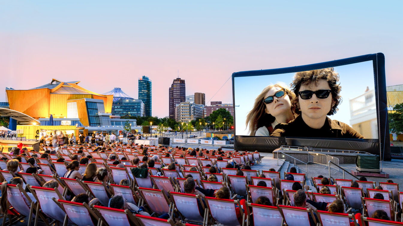 arte Sommerkino (c)Yorck Kinogruppe Freiluftkino in Berlin mit unzähligen Liegestühlen davor. Im Hintergrund sind Hochhäuser zu sehen.