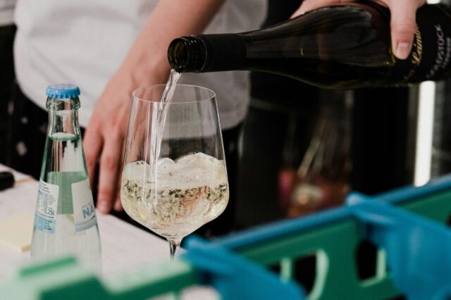 eine Person gießt Wein in ein Weinglas