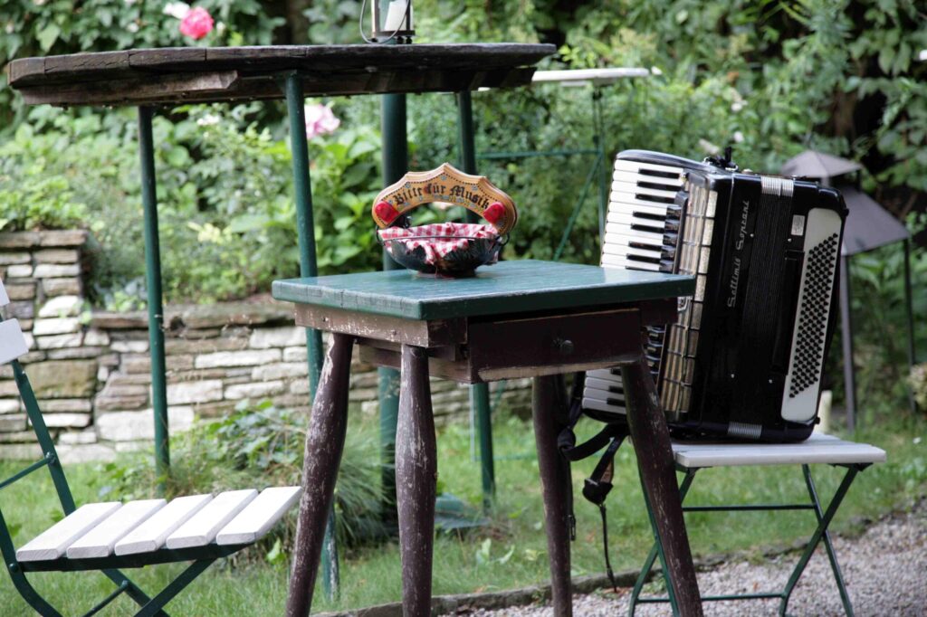 eine Ziehharmonika steht auf einem Sessel in einem urigen Heurigen-Gastgarten in Wien