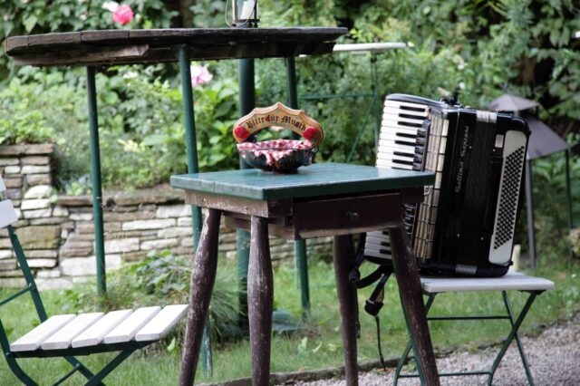 eine Ziehharmonika steht auf einem Sessel in einem urigen Heurigen-Gastgarten in Wien