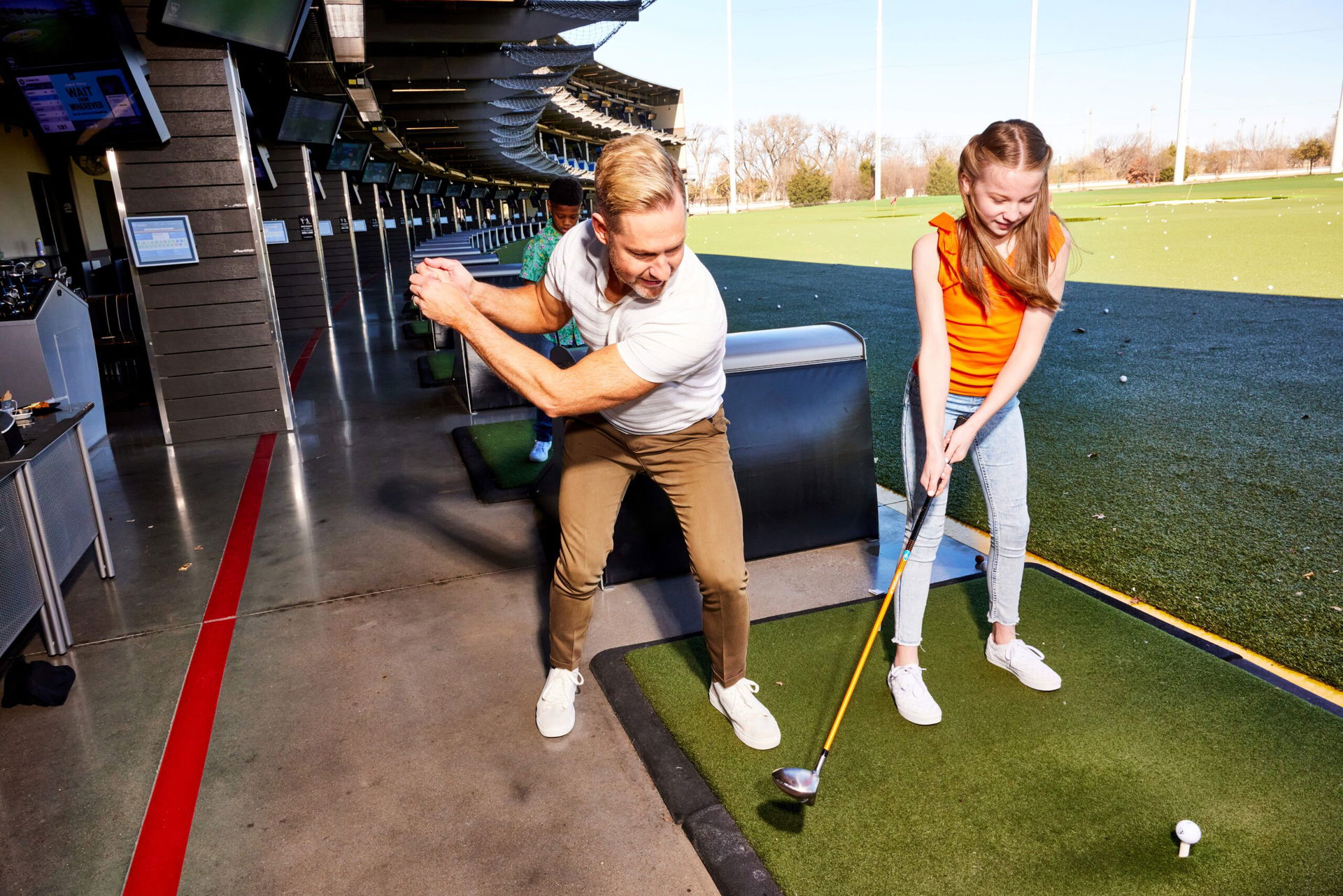 Mann zeigt Mädchen wie man Golf spielt