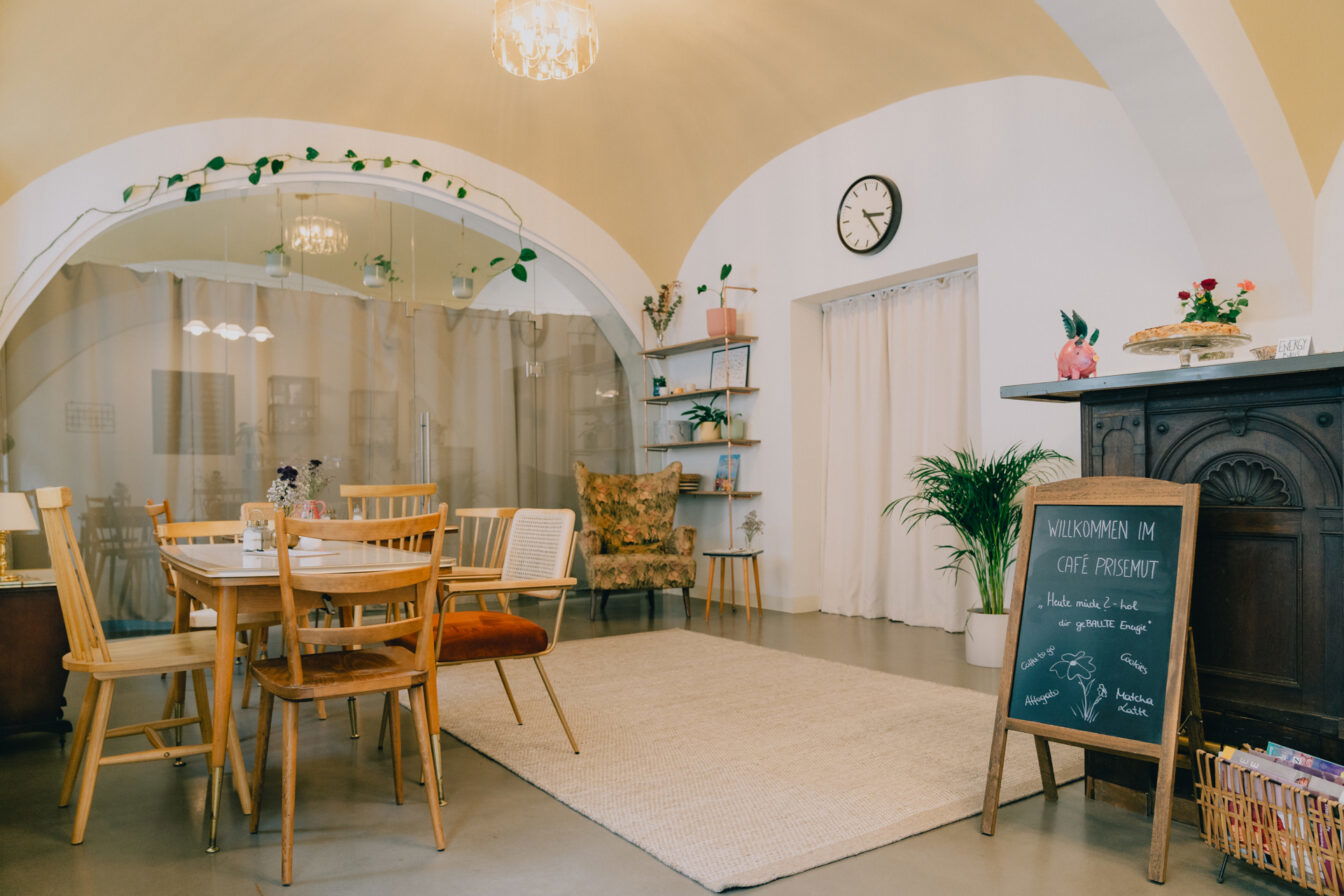 ein Tisch mit Sesseln und Einrichtungsgegenständen im Café PriseMUT in Wien