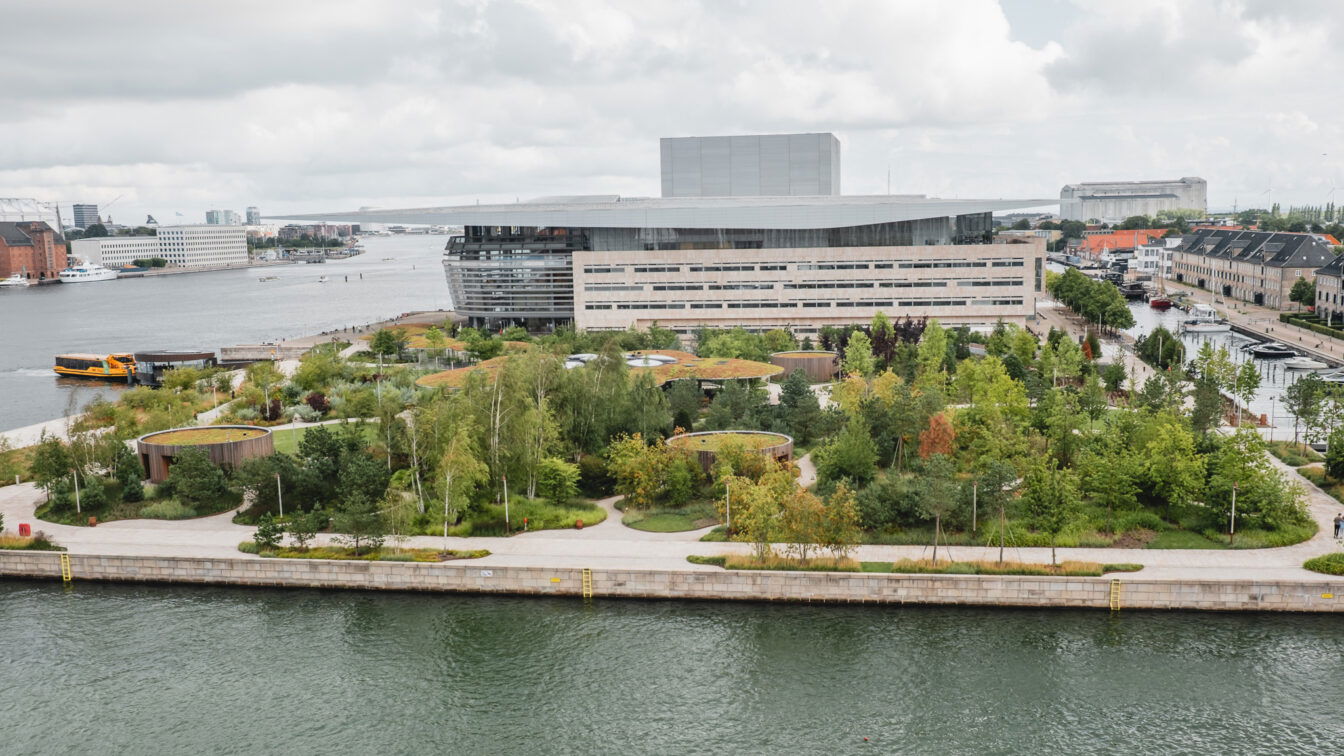 (c) Lilli Wermuth | 1000things Blick auf ein modernes Gebäude mit umgebendem Park am Wasser
