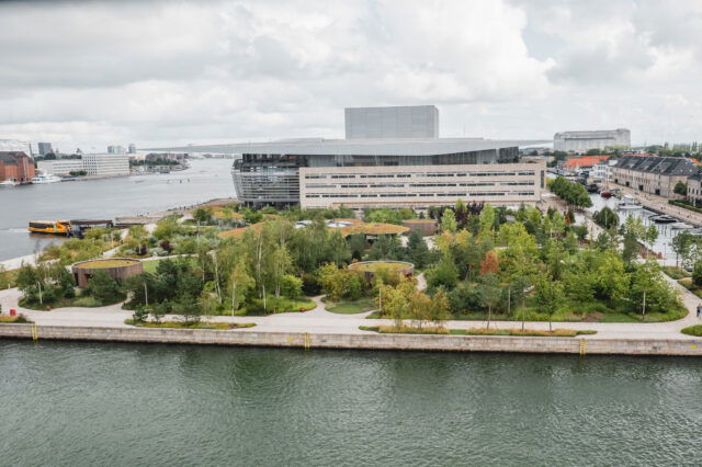 (c) Lilli Wermuth | 1000things Blick auf ein modernes Gebäude mit umgebendem Park am Wasser
