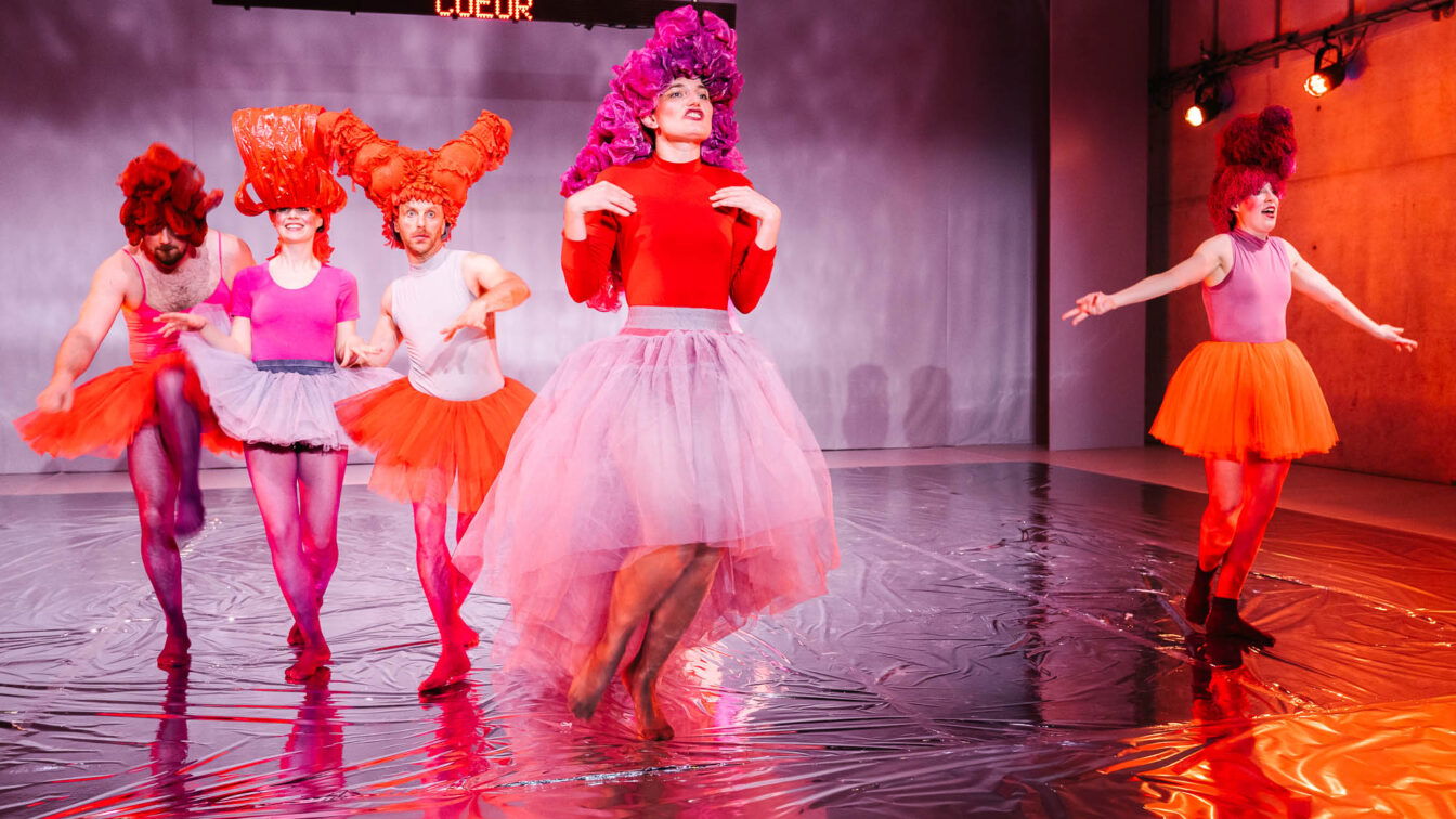 Personen in bunten Kleidern und Röcken in einem Theaterstück