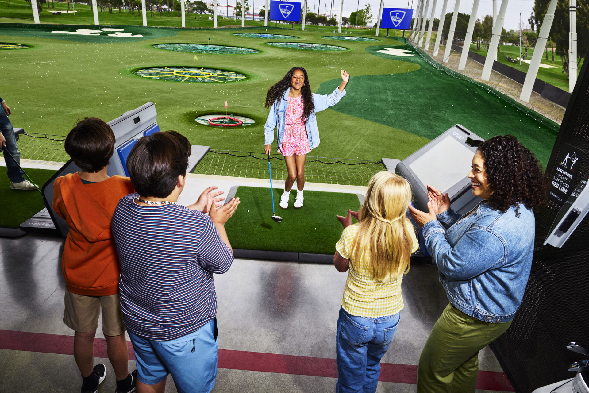 Eine Familie mit vier Kindern spielt Golf bei Topgolf