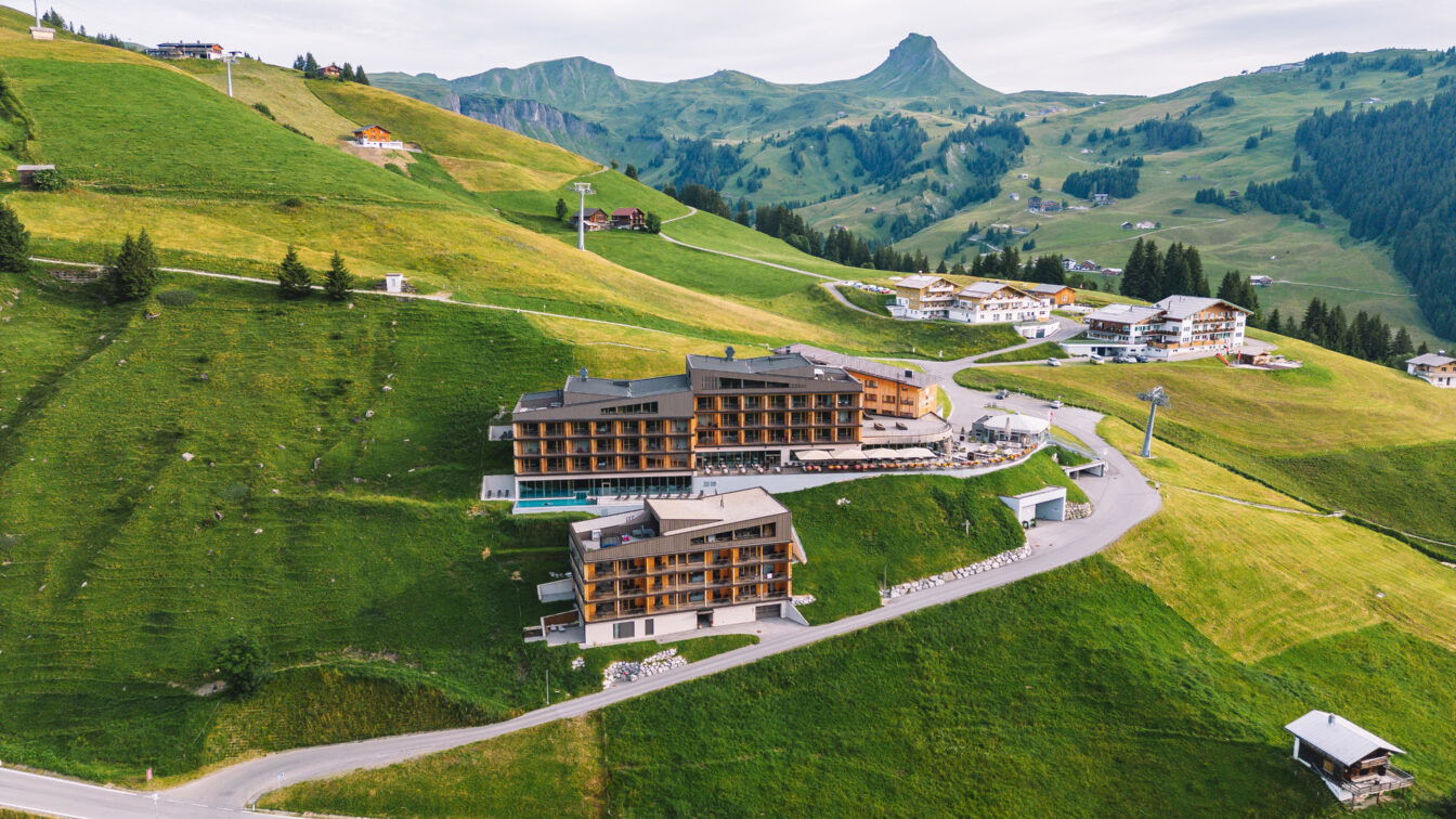 (c) Robert Bohnke Ein Hotelkomplex auf einem Berg in Vorarlberg mit Pool und viel Holz.