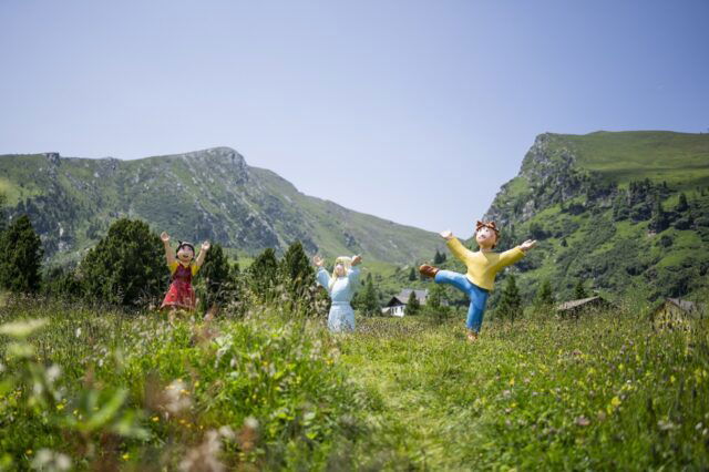(c) Gert Perauer Drei bunte Figuren aus einem Kinderfilm auf einer Blumenwiese mit bergen im Hintergrund