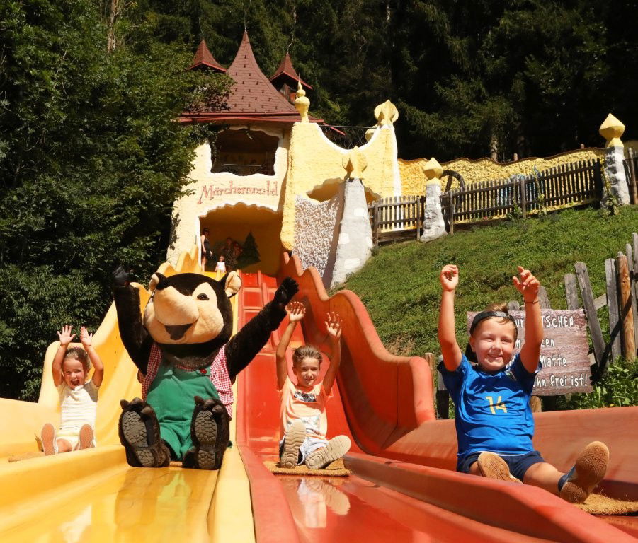 Kinder und ein Maskottchen auf einer bunten Rutsche