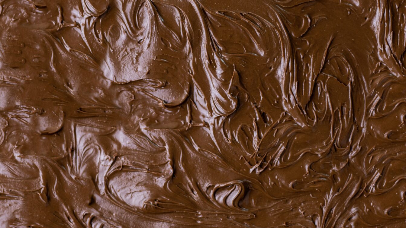 Nahaufnahme von cremig verstrichener Schokoladencreme mit glänzender, glatter und welliger Oberfläche