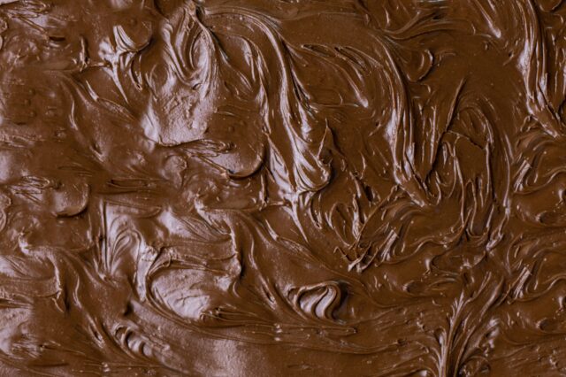 Nahaufnahme von cremig verstrichener Schokoladencreme mit glänzender, glatter und welliger Oberfläche
