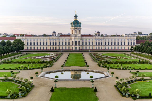 Blick auf ein Schloss mit Fontainenbassin und das Parterre zum Schloss