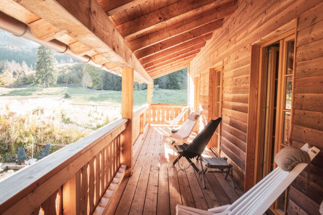 (c) Daniel Breidt Gemütliche Holzveranda mit Liegestühlen in einer Berghütte in den Alpen bei Sonnenschein.