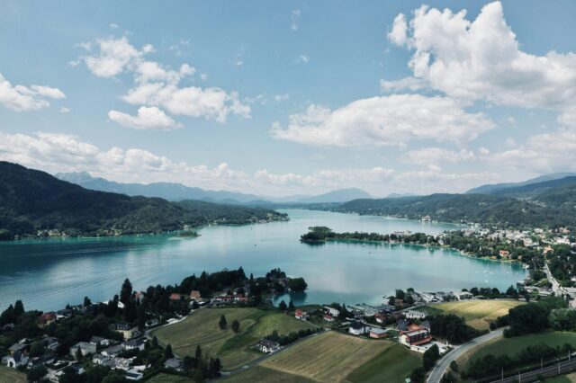 Blick auf einen kleinen Ort am See mit hügeliger Landschaft im Hintergrund