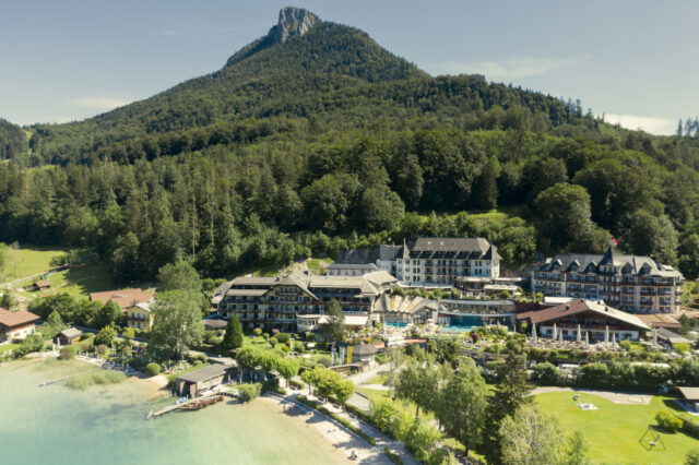 Blick auf Seehotel mit Bergpanorama.