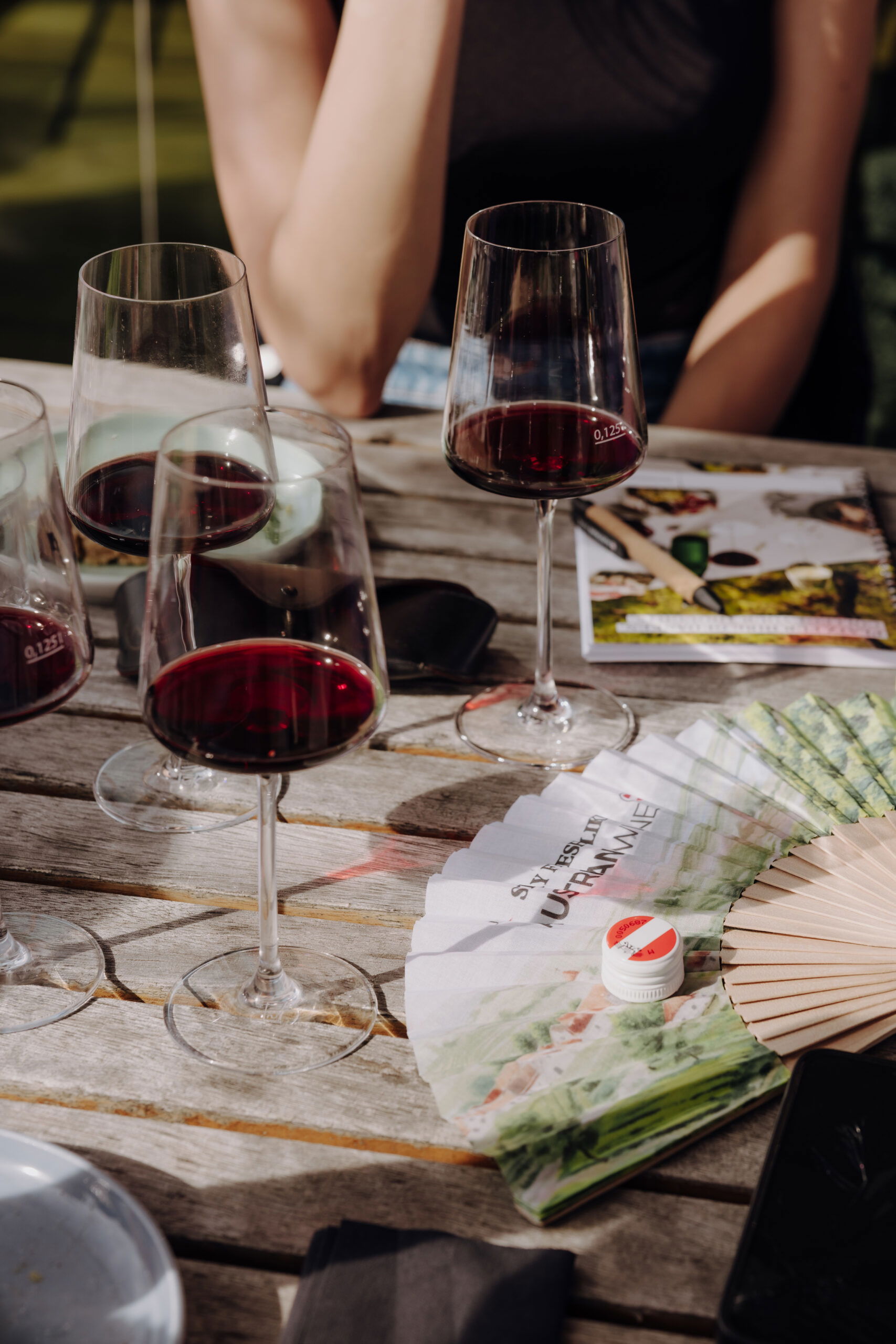 Rotweingläser am Tisch mit Menschen (c) ÖWM | VanDeHart