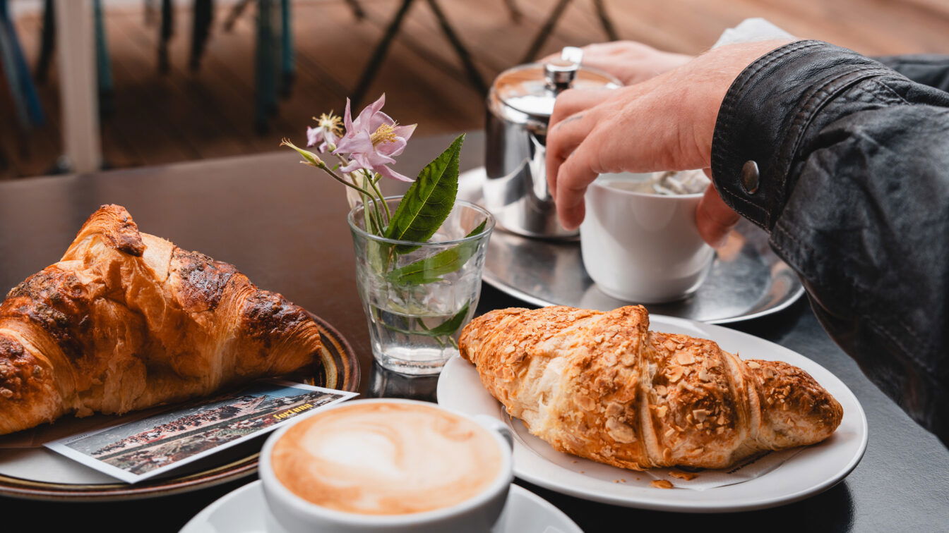 Ein gedeckter Cafétisch mit Kaffee und Croissants in München.