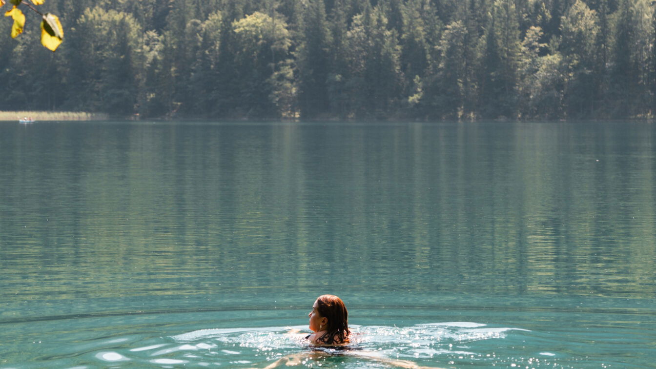 (c) Lisa Oberndorfer | 1000things Baden im türkisblauen See mit Wald im Hintergrund