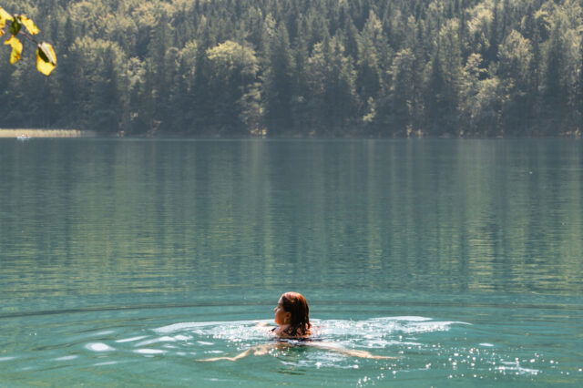 Baden im türkisblauen See mit Wald im Hintergrund