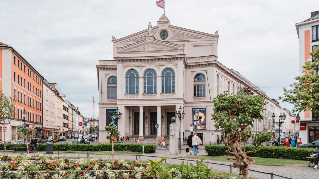 (c) Lilli Wermuth | 1000things Blumenbeete auf einem runden Platz vor einem imposanten Theater im Glockenbachviertel München.