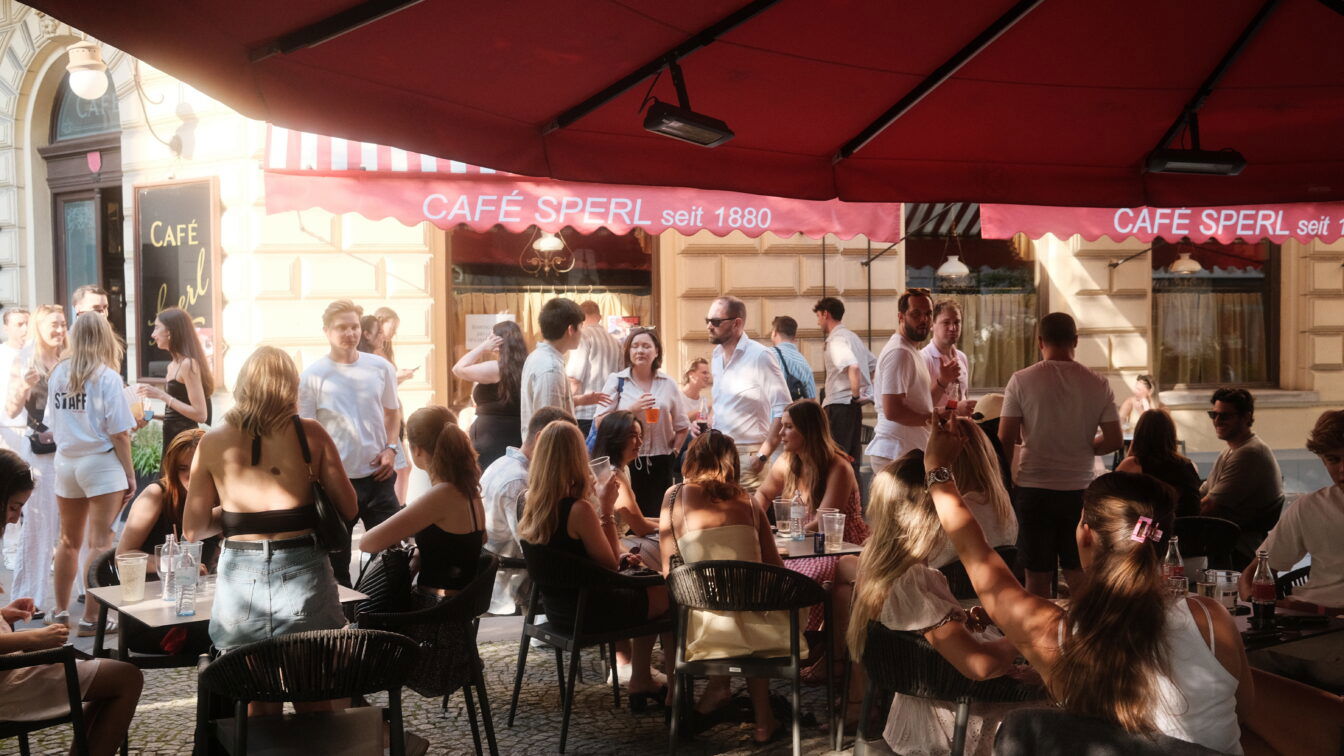 (c) Hot Honey Club Eine Menge junger Menschen vor einem Wiener Kaffeehaus im Gastgarten.