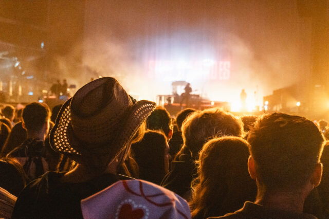 Menschenmenge bei Konzert mit Bühnenbeleuchtung, Festival-Atmosphäre wie bei einer Party in Berlin Friedrichshain, Open-Air-Event mit Livemusik